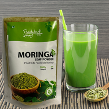 Load image into Gallery viewer, Moringa leaf powder next to a glass of fresh moringa juice, showcasing vibrant green color and promoting health benefits-Poombukar
